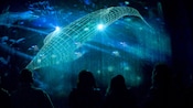 A group of people look at a holographic projection of a whale