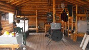 Four sets of bunk beds, a coal heater, tables and other vintage items are inside a log cabin