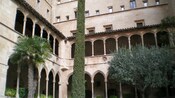 The architecture of a building includes rows of arches supported by columns on the first and second story