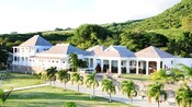 Um caminho em um campo de golfe atravessa uma fileira de palmeiras até um grande prédio do clube
