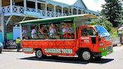An open air tour bus filled with passengers stopped on a street in St. Kitts
