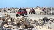 A group of people ride ATVs through a field of boulders