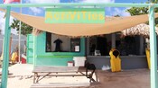 A storefront with a picnic table, paddle boards, a wetsuit and a sign that reads Activities