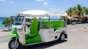 A tuk-tuk near a seating area and a waterfront