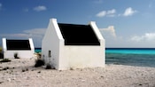 2 white houses with black roofs on a rocky beach