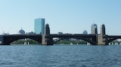 An old bridge in front of modern looking city buildings