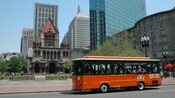 Trolley passing a medieval church dwarfed by skyscrapers