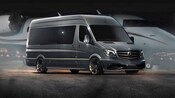 A Mercedes Benz van with tinted windows parked in front of a plane