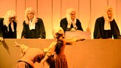 2 animatronic witches standing before a panel of animatronic judges
