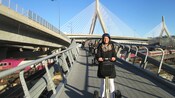 People wearing helmets and riding Segways across a bridge