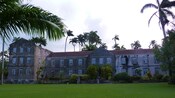 A Barbados stone mansion with a manicured lawn and accent plants and trees