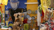 Doorway framed by t-shirts on racks, patterned plates, tote bags and other souveniers