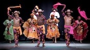 7 performers dance on stage while a band plays behind them