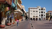 People walk by 17th century colonial buildings in a plaza in old town Cartagena