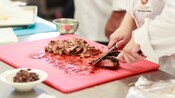 A person slicing meat on a cutting board