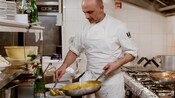 Un hombre en una cocina coloca la pasta en un tazón