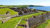 Massive stone fortifications with grassy banks along a coastline