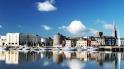 A harbor with boats along the dock and old European style buildings
