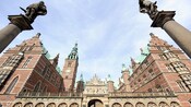 Statues on columns stand at the entrance of Frederiksborg Castle in Copenhagen
