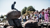 Un grupo turístico toma fotos de la icónica estatua de La Sirenita de Dinamarca