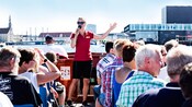 Guests listen to a guide atop a canal boat that is cruising through Copenhagen