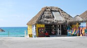 The ocean in the background, a tourist shop with a thatched roof in the front