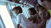 Kids look out the observatory windows on a glass bottom boat