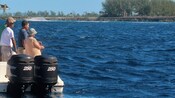 Cuatro pescadores en un bote con líneas de pesca en el agua