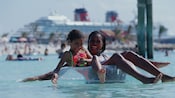A smiling woman and child in swim clothes float in an inflatable tube in a pool