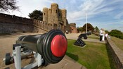 A canon and other artillery in front of a brick tower at Rye Castle, East Sussex, England