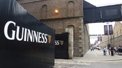 A large sign on a gate at a red brick building identifies the headquarters of Guinness Beer.