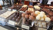 Rows of chocolate candies in the form of truffles, nougats, bars and balls
