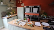 A kitchen featuring ovens, plants, cabinets, an island with food and more