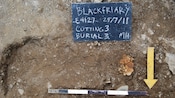A chalk sign on the ground along with an arrow pointing downwards