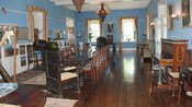 Dining area appointed with wood floors, an antique dining table for 14, a harp, a piano and curtains