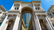An ornate entryway comprised of stone pillars and vaulted glass ceilings