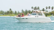 Adults and kids relax on the deck of a small private boat in waters off a tropical island