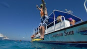 A man in snorkel gear jumping off a boat into the ocean