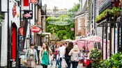 People walking along a cobblestone street flanked with shops and eateries