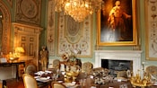 A dining room featuring a set table, chairs, a chandelier, a fireplace, wall art and more