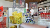 Um homem caminha através de corredores de compras segurando um item