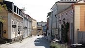 Una calle angosta de adoquines bordeada de edificaciones de madera