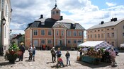 A village town square with cobblestone streets and a produce stand