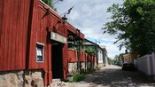 Wooden buildings on a cobblestone street with parked cars, in Porvoo