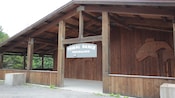 The exterior of a wooden lodge building with a sign that reads Tribal Dance Performance