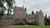 2 people walking out of a 14th-century medieval stone castle