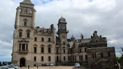 Um grande castelo com pináculos observa um jardim muito bem cuidado