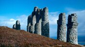 Un monumento de piedra con torres y arcos en una colina verde