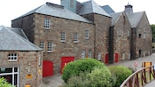 An old sandstone building with carefully tended shrubs in front