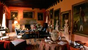 A cozy Renaissance style sitting room with portraiture covering the walls and a fireplace